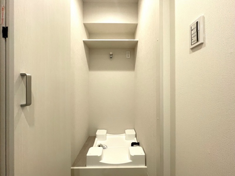 洗面台室奥には洗濯機置き場があり、防水パンと洗濯機専用水栓・コンセント差し込み口が設置され、上部には洗剤やシャンプーストックなどが置ける収納棚も備えてあります。