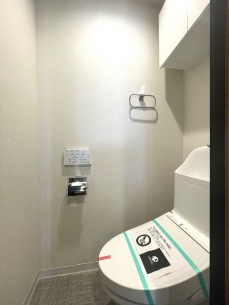 【トイレ】すっきりとしたデザインで清潔感があり、落ち着ける空間です。トイレもうれしいウォシュレット機能付きです。吊戸棚も設置されており、トイレットペーパーなどが収納できます。
