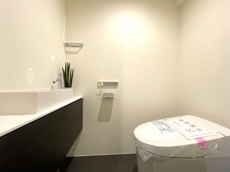 【トイレ】タンクレスですっきりとしたデザインのウォシュレット付きトイレで、室内は清潔感があり落ち着く上質な空間です。吊戸棚も設置されており、トイレットペーパーなどの消耗品の収納ができます。便利な専用手洗いスペースも付いています。