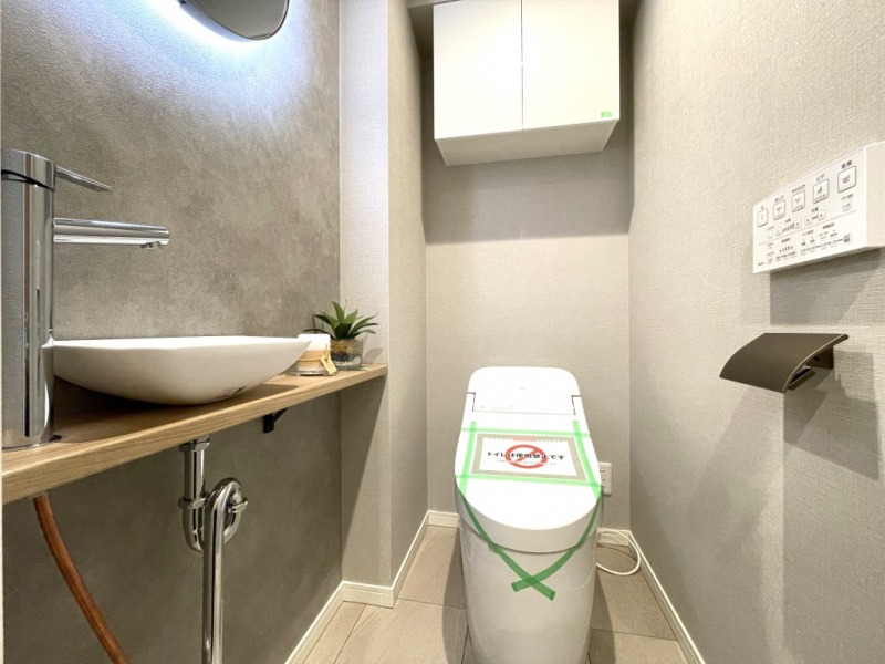 【トイレ】タンクレスですっきりとしたデザインのウォシュレット付きトイレで、室内は清潔感があり落ち着く上質な空間です。吊戸棚も設置されており、トイレットペーパーなどの消耗品の収納ができます。ミラー付の便利な専用手洗いスペースも付いています。