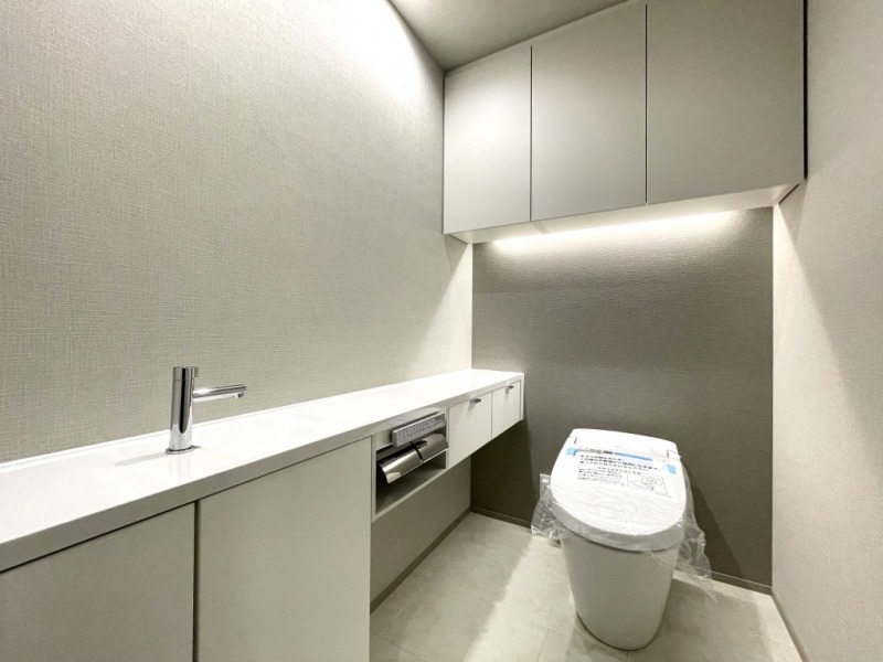 【トイレ】タンクレスのすっきりとしたデザインのウォシュレット付きトイレで、室内は清潔感があり落ち着く上質な空間です。吊戸棚も設置されており、トイレットペーパーなどの消耗品の収納ができます。便利な専用手洗いスペースも付いています。