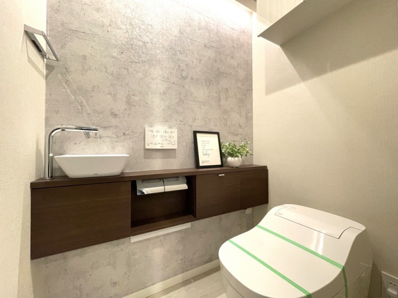 【トイレ】タンクレスのすっきりとしたデザインのウォシュレット付きトイレで、室内は清潔感があり落ち着く上質な空間です。吊戸棚も設置されており、トイレットペーパーなどの消耗品の収納ができます。便利な専用手洗いスペースも付いています。