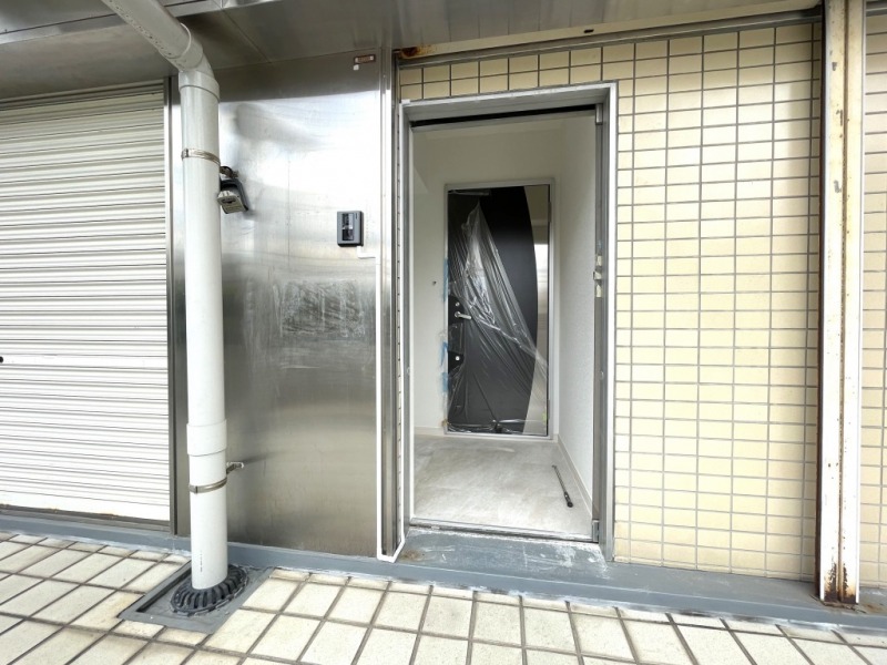 【共用部玄関】商店街の通り沿いのスーパー横の階段を上ると玄関があります。モニター付きインターホンで、来訪者の確認ができます。玄関ポーチのような空間があり、ガラスドアで仕切られています。玄関ドアまでワンクッション置くことによって、プライバシーを守ることができるだけでなく、玄関ドア前を他の住人などが通行することもないので、独立性や防犯性が高まります。