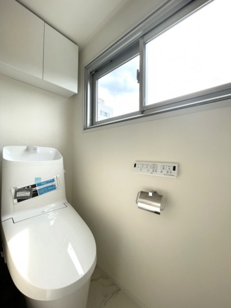 【トイレ】すっきりとしたデザインで清潔感があり、落ち着ける空間です。トイレもうれしいウォシュレット機能付きです。吊戸棚も設置されており、トイレットペーパーなどが収納できます。また窓があるので明るく、こもりがちな臭いも換気ができて快適です。