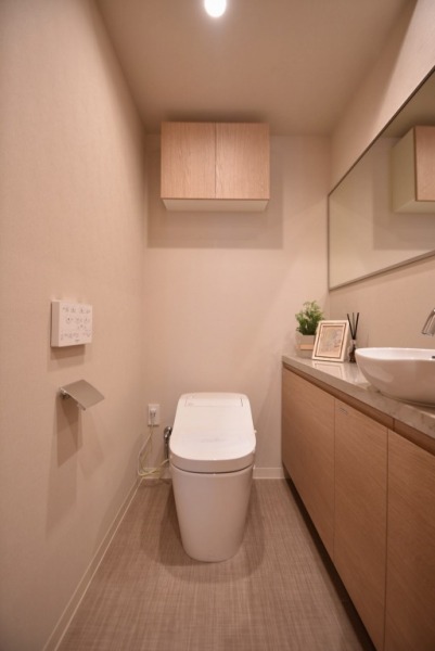 【トイレ】タンクレスのすっきりとしたデザインのウォシュレット付きトイレで、室内は清潔感があり落ち着く上質な空間です。吊戸棚も設置されており、トイレットペーパーなどの消耗品の収納ができます。ワイドミラーも付いた便利な専用手洗いスペースも付いています。