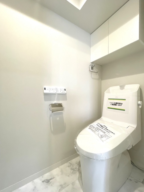 【トイレ】すっきりとしたデザインで清潔感があり、落ち着ける空間です。トイレもうれしいウォシュレット機能付きです。吊戸棚も設置されており、トイレットペーパーなどが収納できます。