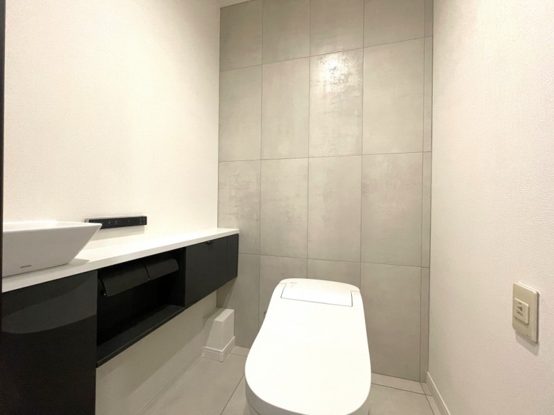 【トイレ】タンクレスのすっきりとしたデザインのウォシュレット付きトイレで、室内は清潔感があり、シックで落ち着く上質な空間です。便利な専用手洗いスペースも設けられています。