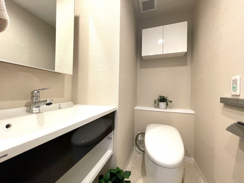 【トイレ】タンクレスのすっきりとしたデザインのウォシュレット付きトイレで、室内は清潔感があり落ち着く上質な空間です。吊戸棚も設置されており、トイレットペーパーなどの消耗品の収納ができます。ミラー付の便利な専用手洗いスペースも付いています。