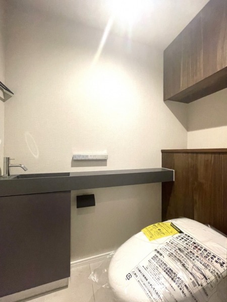 【トイレ】タンクレスのすっきりとしたデザインのウォシュレット付きトイレで、室内は清潔感があり落ち着く上質な空間です。吊戸棚も設置されており、トイレットペーパーなどの消耗品の収納ができます。便利な専用手洗いスペースも付いています。