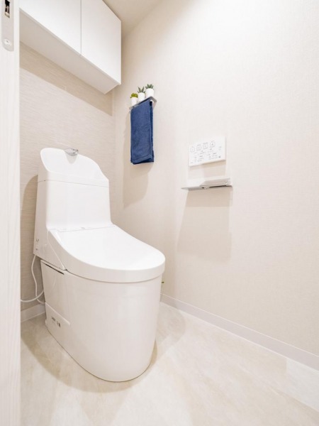 【トイレ】すっきりとしたデザインで清潔感があり、落ち着ける空間です。トイレもうれしいウォシュレット機能付きです。吊戸棚も設置されており、トイレットペーパーなどが収納できます。