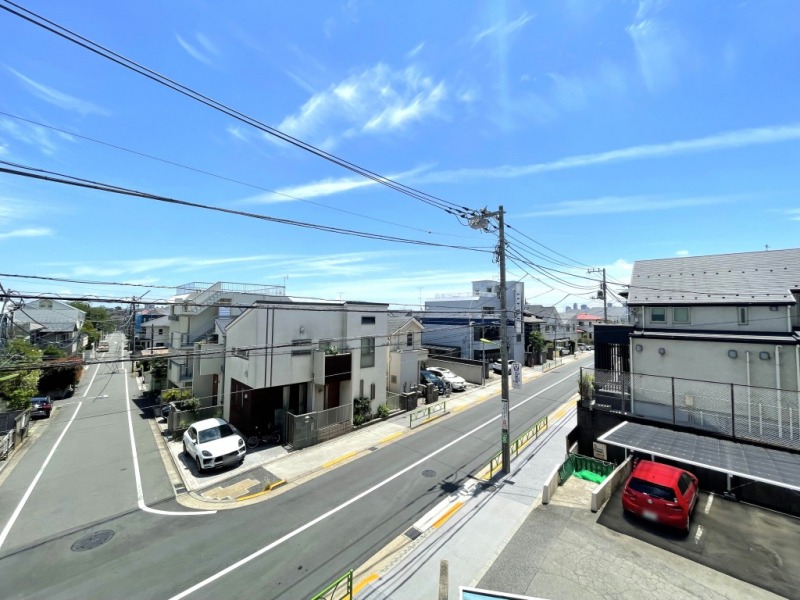 【洋室側バルコニーからの眺望】眼下は駐車場と道路で、前面は低層の建物が多く、視界の開けた眺望です。広い空も仰げます。