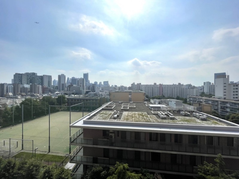 【バルコニーからの眺望】眼前は、サッカーコートや低層の建物が多く、開けた眺望です。奥には新宿方面のビル群が一望できます。空も広く仰げます。