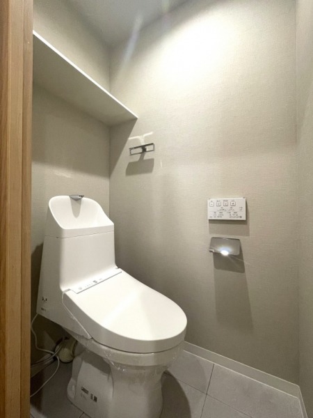 【トイレ】すっきりとしたデザインで清潔感があり、落ち着ける空間です。トイレもうれしいウォシュレット機能付きです。吊棚も設置されており、トイレットペーパーなどが収納できます。