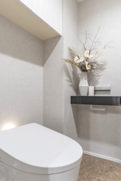 【トイレ】タンクレスのすっきりとしたデザインのウォシュレット付きトイレで、室内はシックなカウンター付きの落ち着く上質な空間です。吊戸棚も設置されており、トイレットペーパーなどの消耗品の収納ができます。便利な専用手洗いスペースも設けられています。