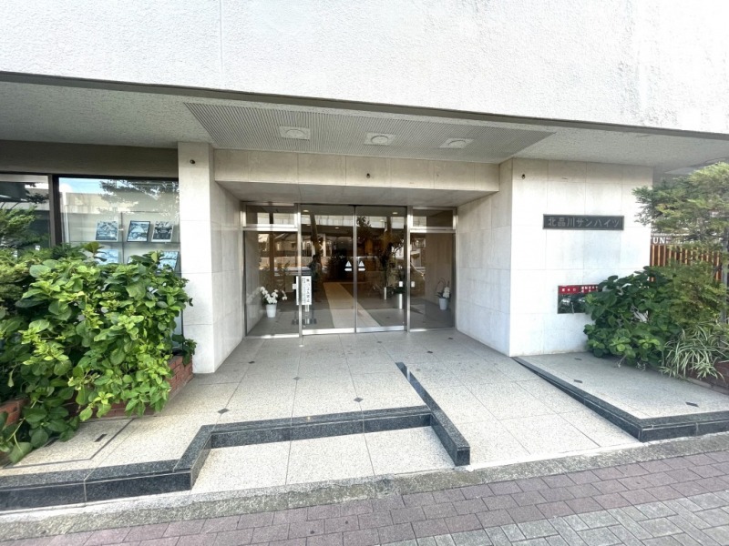 【エントランス】国道15号線沿い並びのテナントや植栽を両脇に、少し奥まったところに位置する、高級感のあるエントランスがあります。スロープが設けられており、ベビーカーや車いすの通行も安心です。