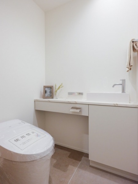 【トイレ】タンクレスのすっきりとしたデザインのウォシュレット付きトイレで、室内は清潔感があり落ち着く上質な空間です。便利な専用手洗いスペースも設けられています。