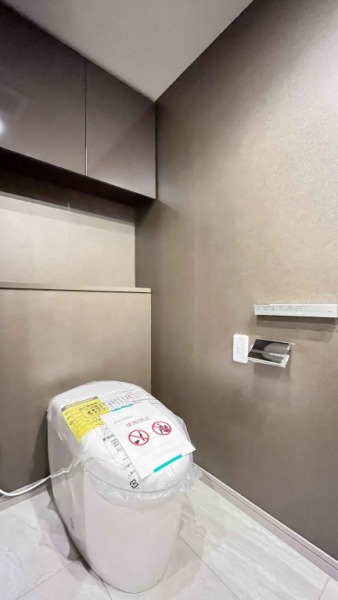 【トイレ】玄関近くのトイレです。こちらもタンクレスのすっきりとしたデザインのウォシュレット付きトイレです。室内は清潔感があり、シックな雰囲気の落ち着く上質な空間です。