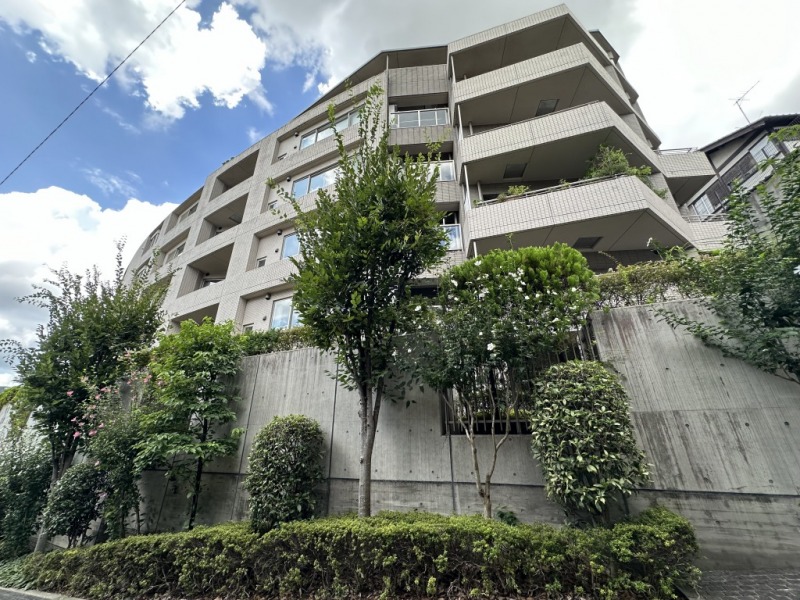 【外観】高級住宅街で知られる目黒区青葉台の高台に位置する、周囲のグリーンに馴染むライトベージュのタイル張りの重厚感のあるL字型の外観です。2002年10月築、佐藤工業施工、新日本建物旧分譲の地上7階建、総戸数34戸のコンパウンド形式のレジデンスです。