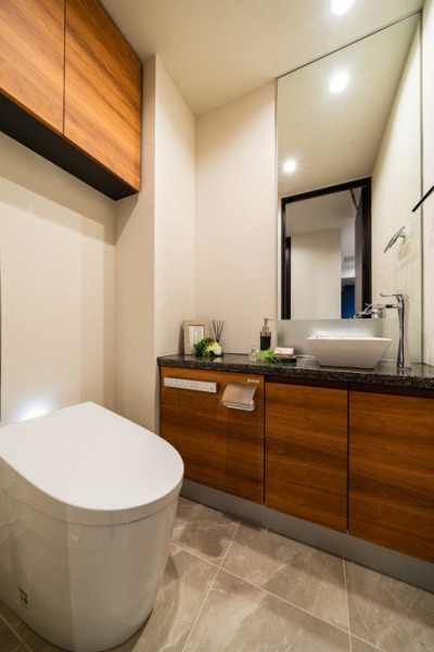 【トイレ】タンクレスのすっきりとしたデザインのウォシュレット付きトイレで、室内はホテルライクな落ち着く上質な空間です。吊戸棚も設置されており、トイレットペーパーなどの消耗品の収納ができます。便利な専用手洗いスペースも設けられています。