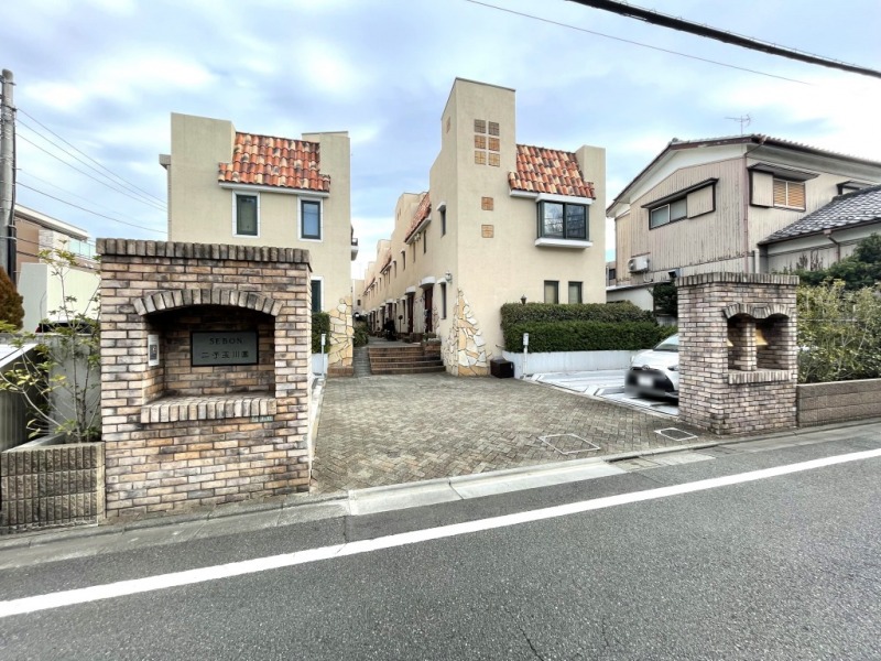 【外観】東急田園都市・大井町線「二子玉川」駅徒歩15分の閑静な住宅街に位置しています。一際目を惹くベージュの壁とスペイン瓦が印象的なヨーロピアンテイストでおしゃれな外観です。2000年1月築、飛鳥建設施工の地下1階付地上2階建、総戸数15戸のメゾネットタイプのタウンハウスです。