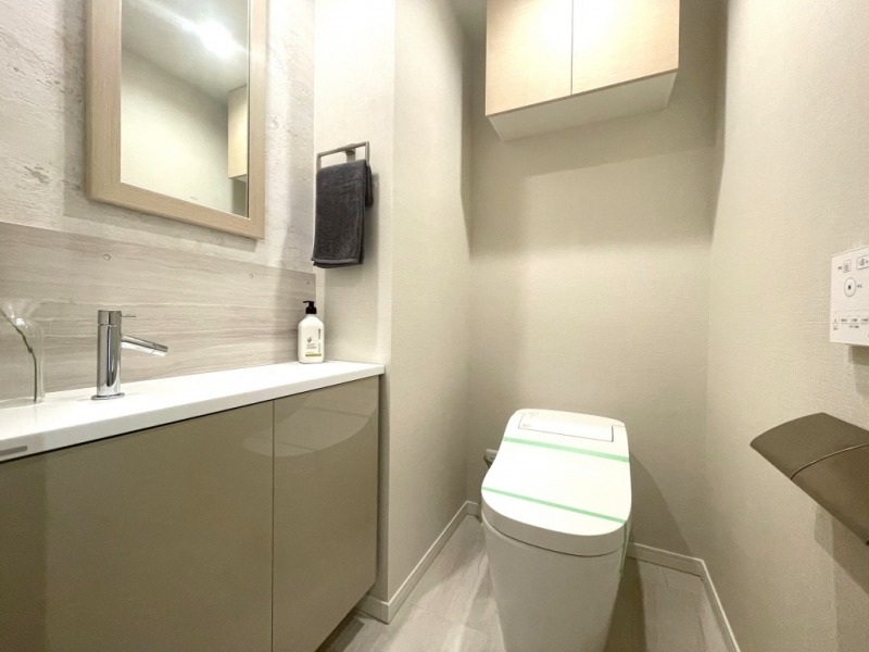 【トイレ】タンクレスのすっきりとしたデザインのウォシュレット付きトイレで、室内は清潔感があり落ち着く上質な空間です。吊戸棚も設置されており、トイレットペーパーなどの消耗品の収納ができます。ミラー付きの便利な専用手洗いスペースも設けられています。