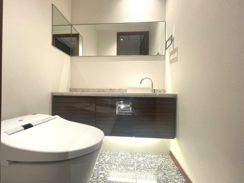 【38階トイレ】タンクレスのすっきりとしたデザインの汚れもつきにくい洗浄付きトイレで、室内は清潔感がありホテルライクな上質な空間です。ワイドミラー付きの便利な専用手洗いスペースも設けられています。