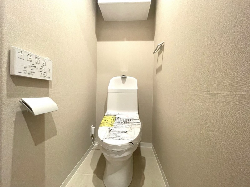 【トイレ】すっきりとしたデザインで清潔感があり、落ち着ける空間です。トイレもうれしい洗浄機能付きです。吊戸棚も設置されており、トイレットペーパーなどが収納できます。