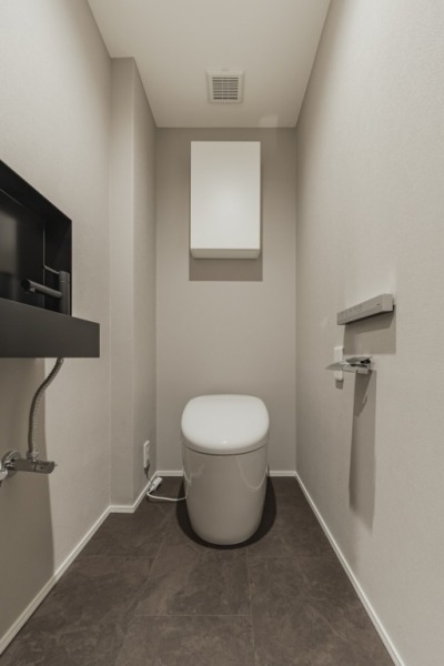 【トイレ】タンクレスのすっきりとしたデザインのウォシュレット付きトイレで、室内は清潔感があり落ち着く上質な空間です。吊戸棚も設置されており、トイレットペーパーなどの消耗品の収納ができます。便利な専用手洗いスペースも設けられています。