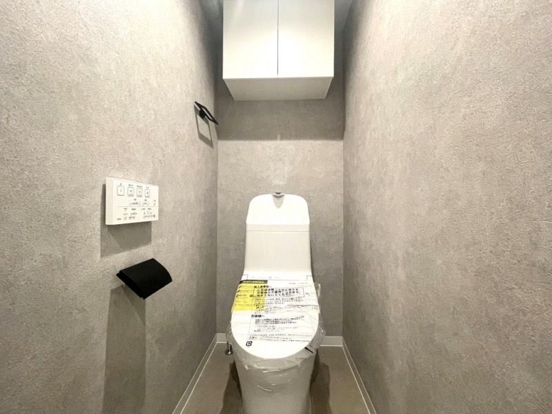 【トイレ】すっきりとしたデザインで清潔感があり、落ち着ける空間です。トイレもうれしいウォシュレット機能付きです。吊戸棚も設置されており、トイレットペーパーなどが収納できます。