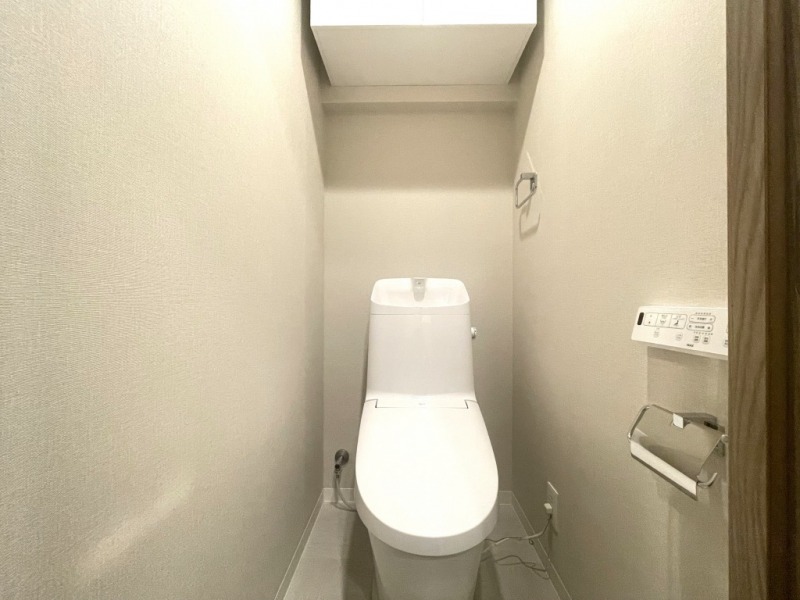【トイレ】すっきりとしたデザインで清潔感があり、落ち着ける空間です。トイレもうれしいウォシュレット機能付きです。吊戸棚も設置されており、トイレットペーパーなどが収納できます。