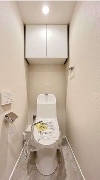 【トイレ】すっきりとしたデザインで清潔感があり、落ち着ける空間です。トイレもうれしい洗浄機能付きです。吊戸棚も設置されており、トイレットペーパーなどが収納できます。