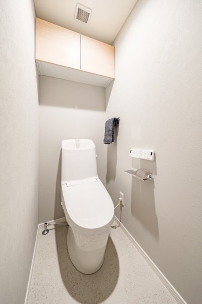【トイレ】すっきりとしたデザインで清潔感があり、落ち着ける空間です。トイレもうれしい洗浄機能付きです。吊戸棚も設置されており、トイレットペーパーなどが収納できます。