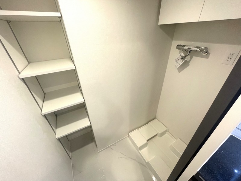 【洗濯置場】洗面室には洗濯機置き場があり、防水パンと洗濯機専用水栓・コンセント差し込み口が設置され、横にはリネン類など収納できるシェルフ、上部には吊戸棚も備えてあり、洗剤やシャンプーストックなども収納できます。引き戸も付いて生活感も出にくく、洗面室もすっきりご利用頂けます。