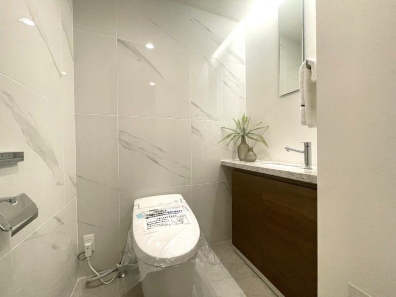 【トイレ】こちらもタンクレスの温水洗浄機能付きトイレで、室内はバスルームと同じ仕様で高級感がありつつ、落ち着く上質な空間です。ミラーとカウンター付きの専用手洗いスペースもあります。