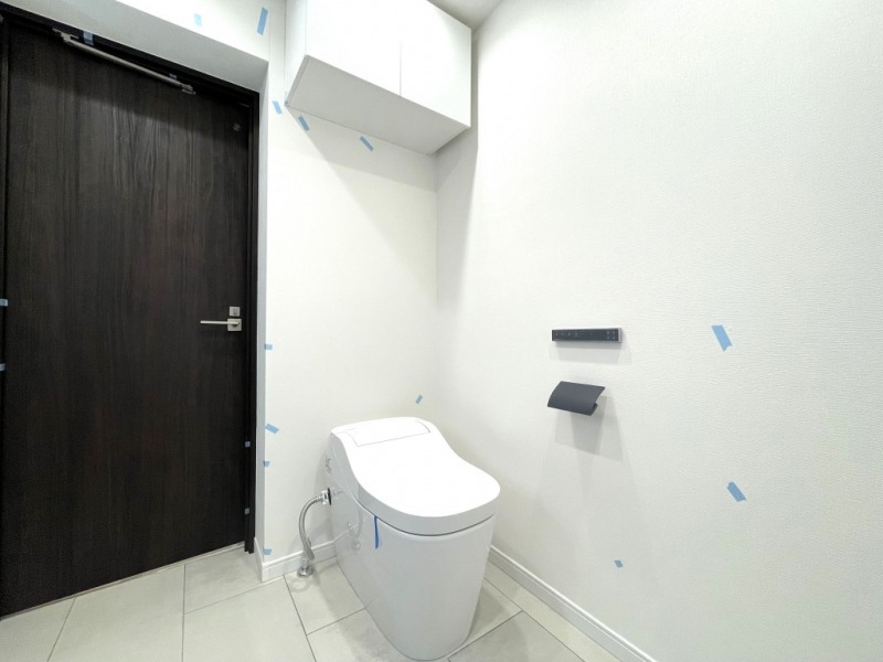 【トイレ】タンクレスでお手入れもしやすいすっきりとしたデザインの洗浄付きトイレは、洗面室に併設されています。清潔感があり上質な空間です。吊戸棚も設置されており、トイレットペーパーやタオルなどの収納ができます。