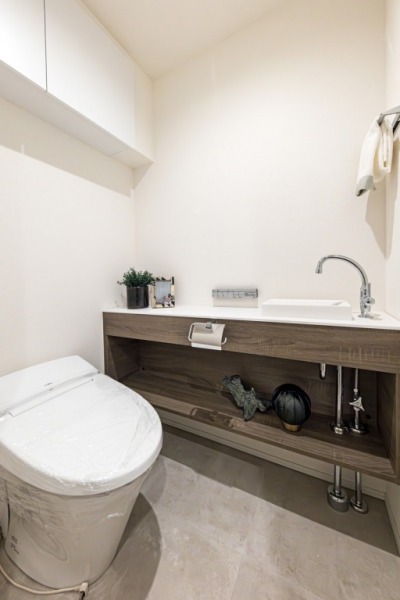 【トイレ】タンクレスでお手入れもしやすいすっきりとしたデザインの洗浄付きトイレで、室内は清潔感があり落ち着く上質な空間です。吊戸棚も設置されており、トイレットペーパーやタオルなどの収納ができます。便利な専用手洗いスペースも設けられています。