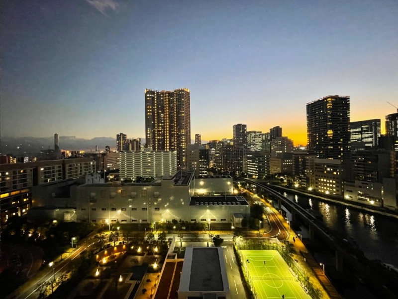 【住戸からの眺望】眼下には、敷地内の公園や居住者専用テニスコート兼フットサルコートがライトアップされています。運河に街の明かりが揺らぎ、その奥には、芝浦や品川のビル群の美しい夜景が広がります。