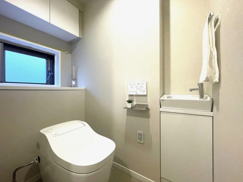 【トイレ】タンクレスの温水洗浄機能付きトイレで、お手入れもしやすくすっきりしていて、室内は清潔感があり落ち着く上質な空間です。吊戸棚も設置されており、トイレットペーパーやタオルなどの収納ができます。便利な専用手洗いスペースも設けられています。また窓があるので明るく、こもりがちな臭いも換気ができて快適です。