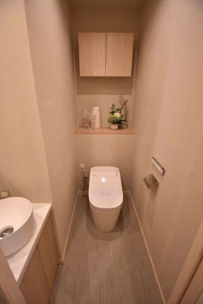 【トイレ】タンクレスの温水洗浄機能付きトイレで、お手入れもしやすくすっきりしていて、室内は清潔感があり落ち着く上質な空間です。吊戸棚も設置されており、トイレットペーパーやタオルなどの収納ができます。便利な専用手洗いスペースも設けられています。