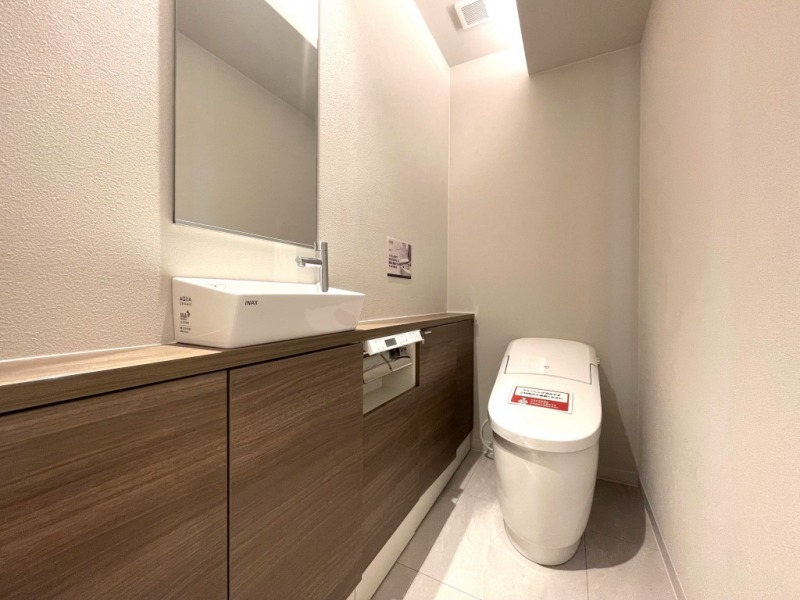 【トイレ】お手入れのしやすいタンクレスで、すっきりとしたデザインの温水洗浄機能付きトイレです。室内は清潔感があり落ち着く上質な空間です。ミラーとカウンター付きの便利な専用手洗いスペースも設けられています。