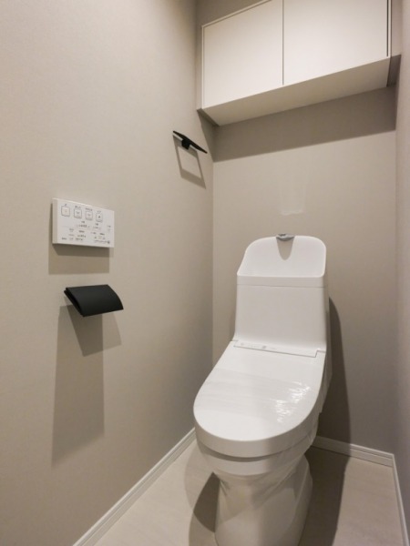 【トイレ】すっきりとしたデザインで清潔感があり、落ち着ける空間です。トイレもうれしい洗浄機能付きです。吊戸棚も設置されており、トイレットペーパーなどが収納できます。