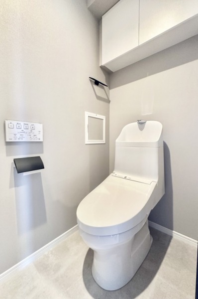【トイレ】すっきりとしたデザインで清潔感があり、落ち着ける空間です。トイレもうれしい洗浄機能付きです。吊戸棚も設置されており、トイレットペーパーなどが収納できます。