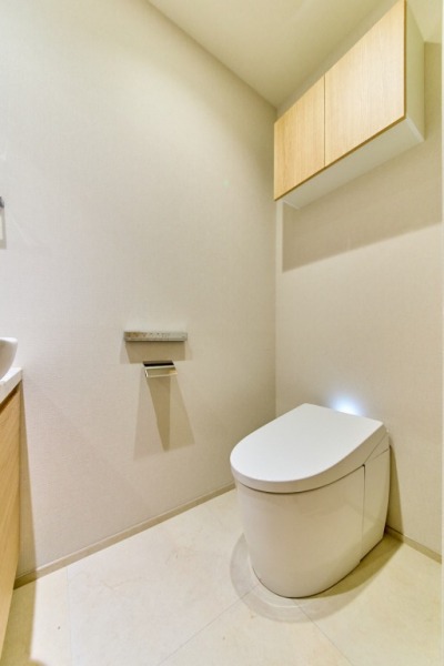【トイレ】タンクレスの温水洗浄機能付きトイレで、お手入れもしやすくすっきりしています。室内は清潔感があり落ち着く上質な空間です。吊戸棚も設置されており、トイレットペーパーやタオルなどの収納ができます。カウンター付き便利な専用手洗いスペースも設けられています。