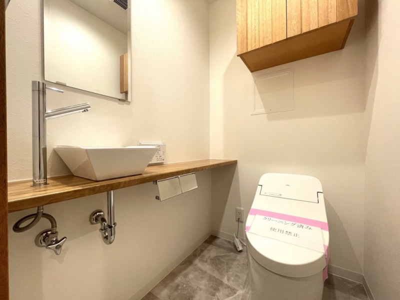 【トイレ】タンクレスですっきりとしたデザインのウォシュレット付きトイレです。室内は天然無垢材の温もりを感じる落ち着いた上質な空間です。ミラー付の便利な専用手洗いスペースが設けられています。