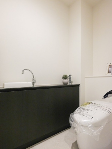 【トイレ】タンクレスの温水洗浄機能付きトイレで、お手入れもしやすくすっきりしています。室内は清潔感があり落ち着く上質な空間です。備品収納が可能なカウンター付きの便利な専用手洗いスペースも設けられています。