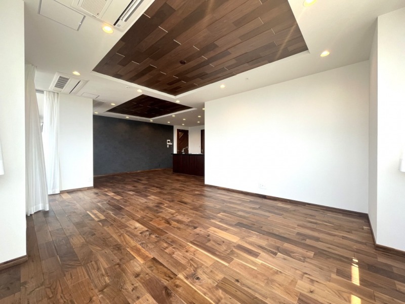 【LDK:約25.0帖】広々としたLDKのフローリングや折り上げ天井、デザイン性のある建具は、天然無垢のウォルナット材をふんだんに使用しています。重厚感のある深い墨絵のような美しい木目は、木のぬくもりを感じます。上質な素材を使って造り上げた空間は、高級感と安らぎをもたらします。