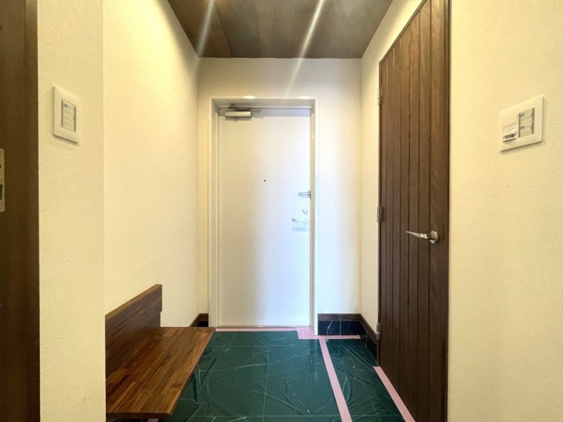 【玄関】玄関の天井や廊下も天然無垢材を使用し、玄関フロアはブラックの石調タイル敷で上品な空間となっています。玄関横には大容量のシューズインクローゼットが備えてあります。買い物した物などの一時的な荷物置きとして利用できる折り畳み式の棚が設けられています。