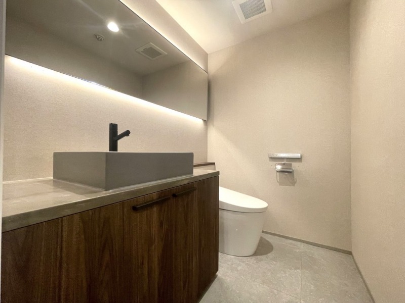【トイレ】お手入れのしやすいタンクレスで、すっきりとしたデザインの温水洗浄機能付きトイレです。室内は清潔感があり落ち着く上質な空間で、ワイドミラーの付いた洗面台が設けられています。玄関土間の横に位置していて、帰宅してすぐに手洗いができ、動線もスムーズです。
