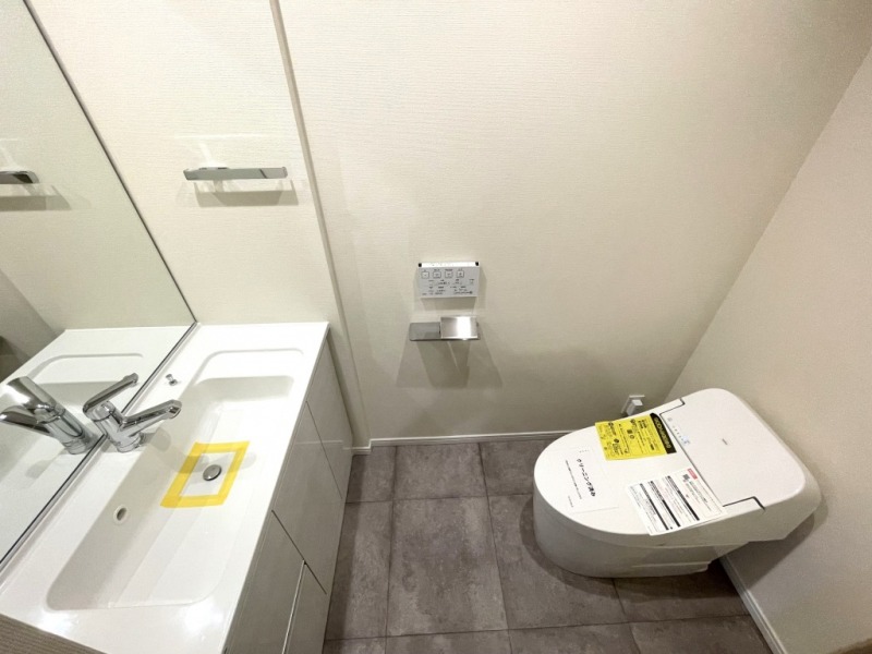 【トイレ】お手入れのしやすいタンクレスで、すっきりとしたデザインの温水洗浄機能付きトイレです。室内は清潔感があり落ち着く上質な空間です。ミラーと収納の付いた便利な専用手洗いスペースも設けられています。