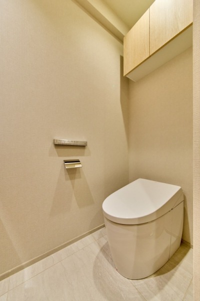 【トイレ】お手入れのしやすいタンクレスで、すっきりとしたデザインの温水洗浄機能付きトイレです。室内は清潔感があり落ち着く上質な空間です。トイレットペーパーなどが収納できる吊戸棚も設置されています。便利な専用手洗いスペースも設けられています。